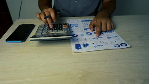 Person using a calculator and analyzing financial charts on paper Video stock 315983077