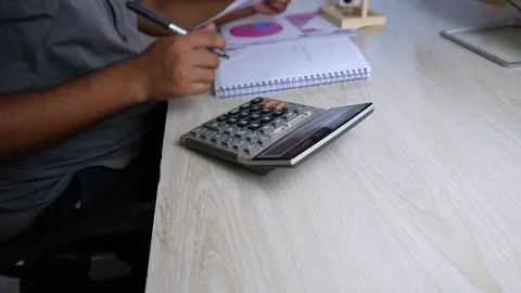 Person Using Calculator and Taking Notes at Desk Stock Footage 315982837