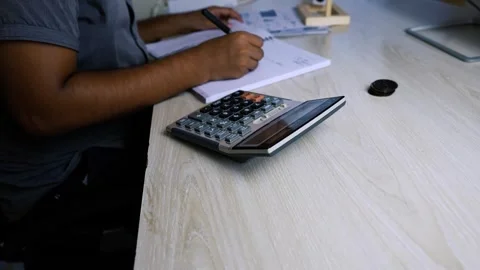 Person Using Calculator and Taking Notes at Desk Stock Footage 315982850