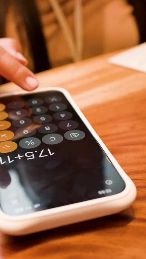 Person Using Calculator App on Smartphone at Restaurant Table Stock Footage 345219594