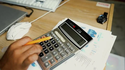 Person using a calculator on a desk with documents and a watch Video stock 315981827