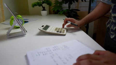 Person using a calculator on a desk with a notebook and pen Stock Footage 317737050