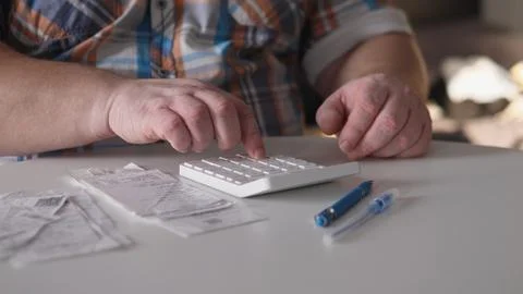 Person using a calculator while sitting at a table with receipts and pens in a Foto stock