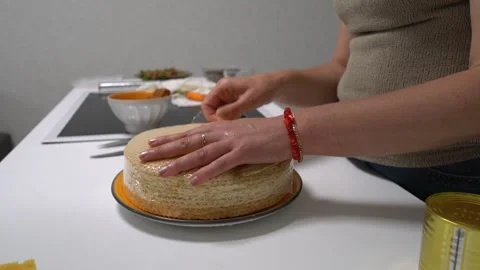 A person is using a can opener to open a tin, likely honey, next to a stack of Stock Footage 336446152