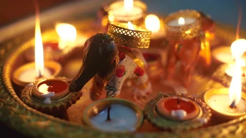 Person using a candle to light diyas on a plate with a beautiful elephant in the Stock Footage 143417170