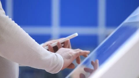 Person is using a cell phone in front of a blue wall Stock Footage 304772923