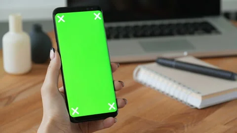 Person using cell phone with green screen display in hand and woman make a gestu Stock Footage 199491209