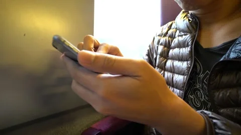 A person is using a cell phone while sitting on a train Stock Footage 314594095