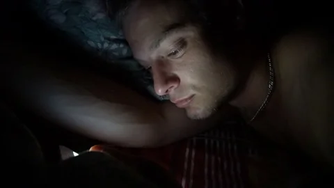 Person using cellphone in bed. Smiling Man using smartphone mobile cellphone in Stockbeeldmateriaal 78809206