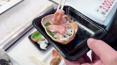 Person using chopsticks to pick up delicious crab meat from a crab shell dish 스톡 동영상 334365302