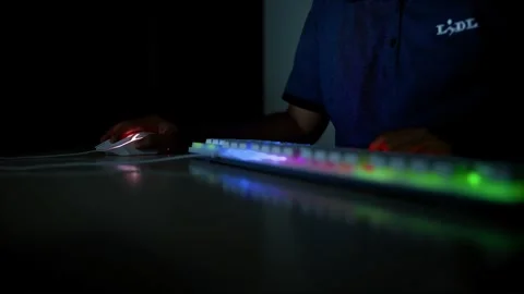 Person using a computer with a colorful backlit keyboard in a dark room Stock Footage 317736830