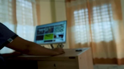 Person using a computer in a dimly lit room with curtains Stock Footage 315981355