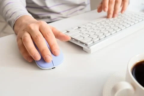 Person using computer mouse and keyboard with coffee cup Foto stock