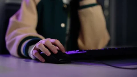 Person using computer mouse at desk in purple light 動画素材 348029463