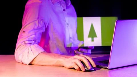 Person using computer with Norfolk Island emblem projection in violet glow 스톡 사진