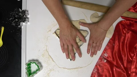 A person is using a cookie cutter to shape dough into Christmas tree patterns on Stock Footage 336066795