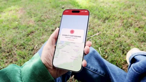 Person using earthquake app on mobile phone for real-time emergency alert - Video stock 339506795