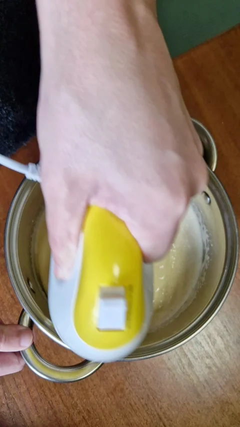 Person Using Electric Hand Mixer to Blend Batter in Stainless Steel Pot Stock Footage 338999522