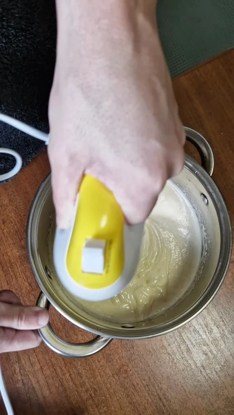 Person Using Electric Hand Mixer to Blend Creamy Batter in Metal Cooking Pot Stock-Footage 339001904