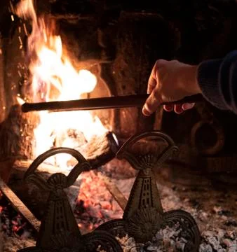 Person using a fire iron to stoke the flames Stock Photos
