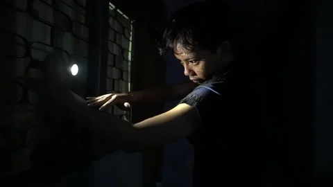 Person Using Flashlight to Look Through Window at Night Stock Footage 313467766