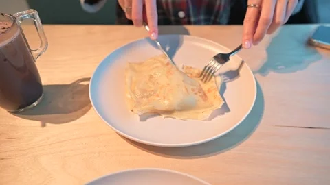 A person using a fork and knife cuts a homemade dish on a plate at a dinner Vidéo 339005040