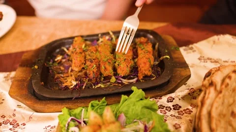 Person Using Fork to Eat Grilled Seekh Kebabs on Sizzler Plate Stock Footage 337224970