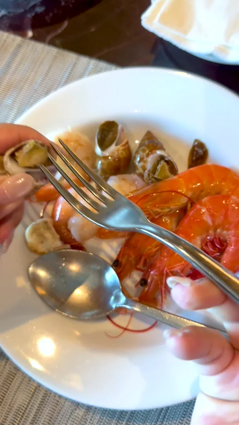 Person Using Fork to Extract Snail Meat from Shell at Buffet Stock Footage 335620623