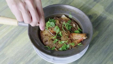 Person using a fork to pick up glass noodles from a traditional Thai casser.. Stock-Footage 334545810