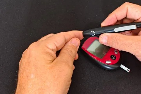 Person Using a Glucose Meter to Check Blood Sugar levels Stock Photos