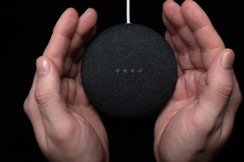 Person using a Google Home Mini charcoal smart speaker Stock Photos