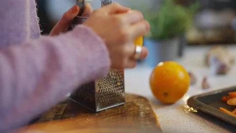 A person is using a grater to grate an orange Stock Footage 295367715