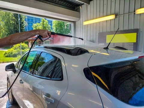A person is using a handheld high-pressure water sprayer to wash the roof Stock Photos