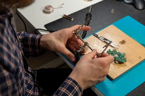 A person using a helping hands tool for a DIY project at a workbench Stock Photos