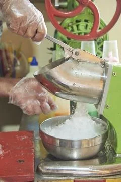 Person using an ice crusher machine to make a raspado, cool Colombian snack Stock Photos