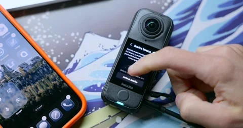 Person Using Insta360 X4 Camera While Charging Stockbeeldmateriaal 327521218