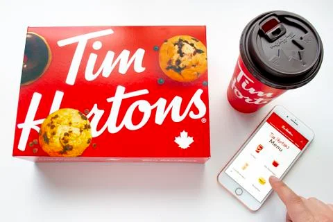A person using an iPhone Plus using the Tim Hortons app with a coffee and a box  Stockfoto's