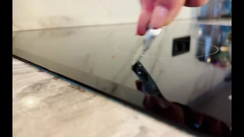 A person is using a knife to cut a piece of paper on a stove Vidéo 279056964
