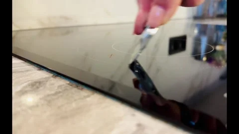 A person is using a knife to scrape off a stain on a stove top Vidéo 276309862