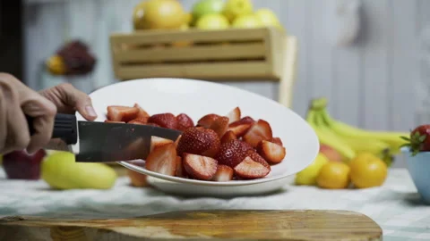 Person using knife to scrape strawberries from plate to cutting board, closeup Stock Footage 341184185
