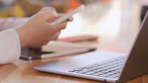 Person is using a laptop and a cell phone Stock Footage 316975823