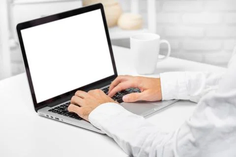 Person using a laptop in a bright workspace during the daytime while enjoying a 스톡 사진