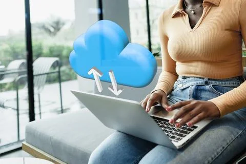 Person using laptop with cloud upload symbol in modern setting near window in 스톡 사진