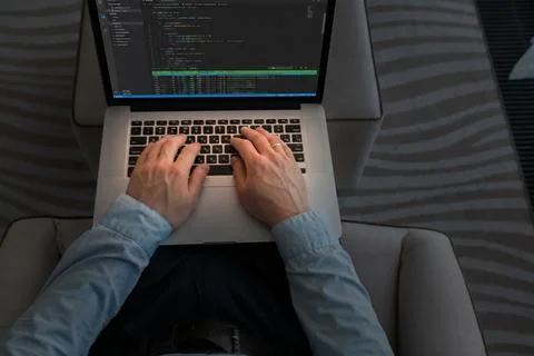 Person using a laptop to code while sitting in a modern workspace during the day Foto stock
