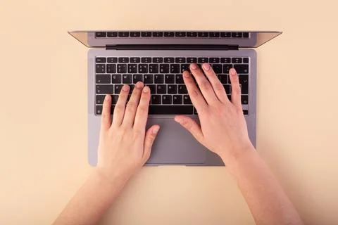 Person using a laptop computer on beige background. Flatlay, concept freela.. Stock Photos