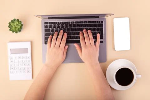 Person using a laptop computer, calculator, cup of coffee and smartphone on.. Stock Photos