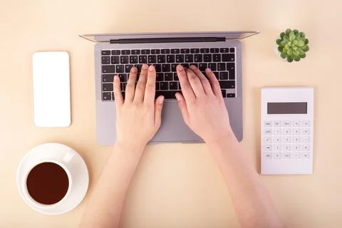 Person using a laptop computer, calculator, cup of coffee and smartphone on.. 库存照片