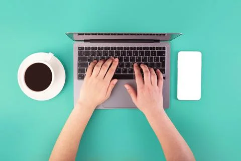Person using a laptop computer, cup of coffee and smartphone on green backg.. 库存照片