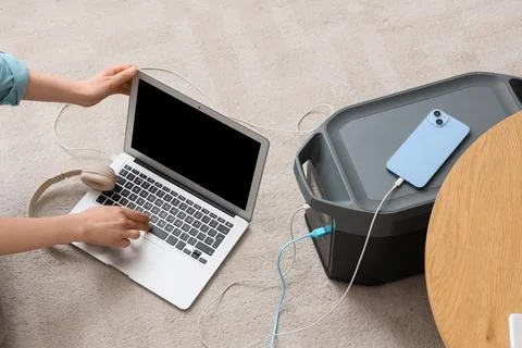 Person using laptop connected to portable power station with smartphone charg Stock Photos