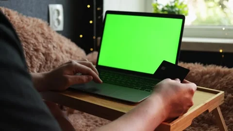 Person using laptop with green screen and credit card for online shopping Stock Footage 340264776